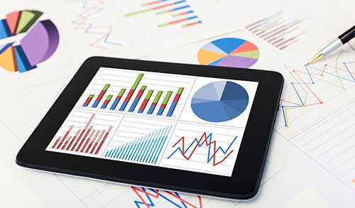 Papers with spreadsheets, graphs, and an mobile pad device with spreadsheets