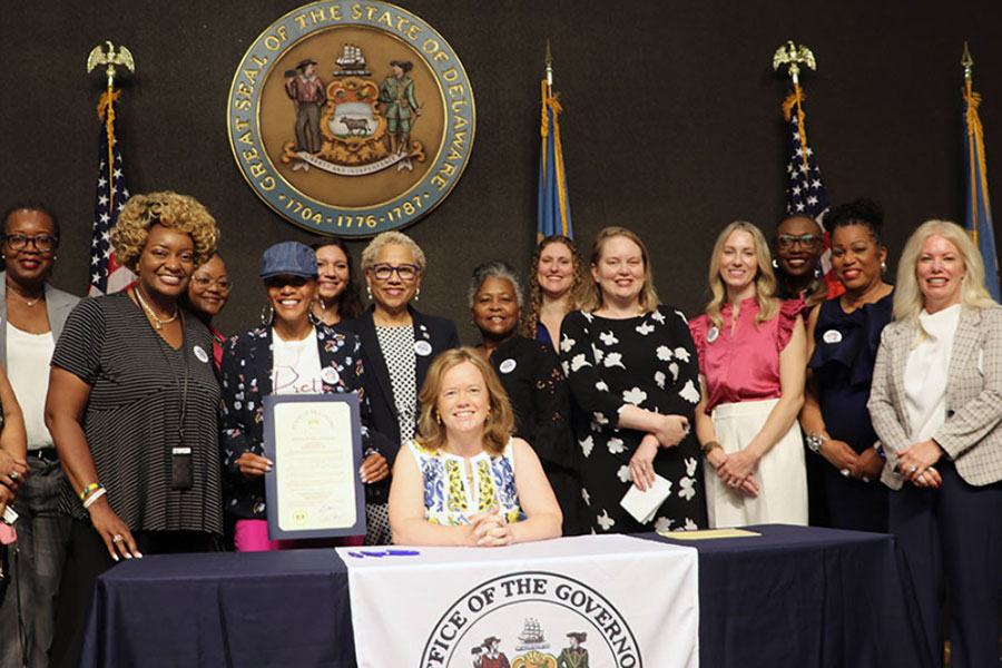 Group of women standing behind the Office of Women's Advancement and Advocacy banner.